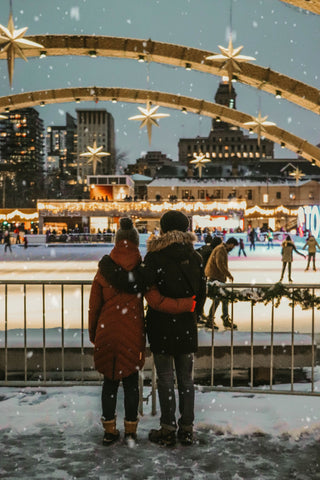 Two people overlooking ice skating rink