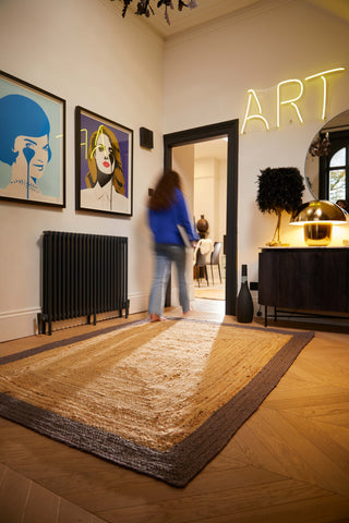 woman walking over a large border jute rug in hallway