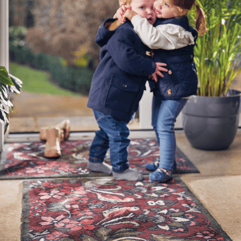 Two children giving each other a hug at the front door