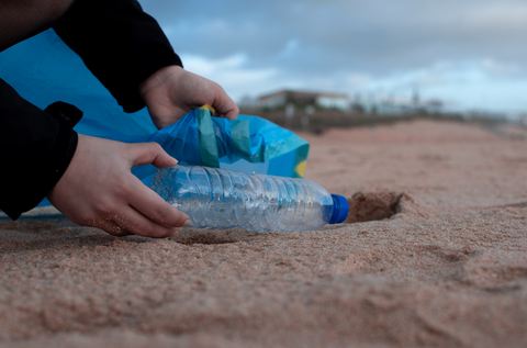 Plastic bottle being picked up from beach