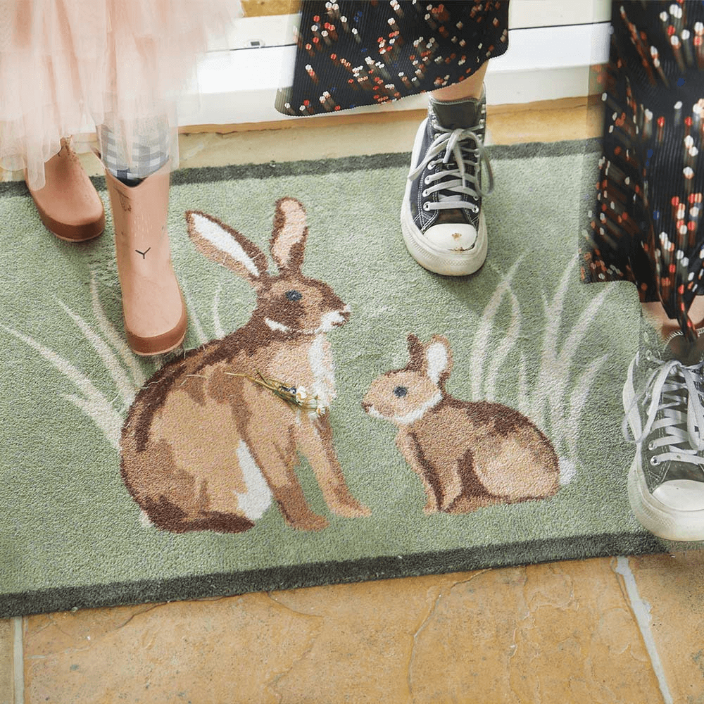 People walking over a front door mat with a rabbit design