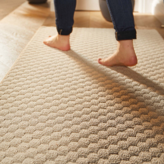 Someone walking across an ivory sculptured runner with bare feet