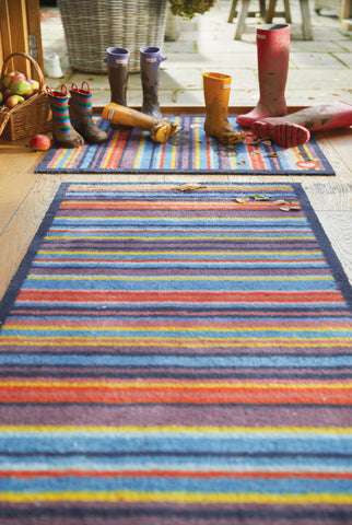 A striped front door mat and runner with muddy wellies on top