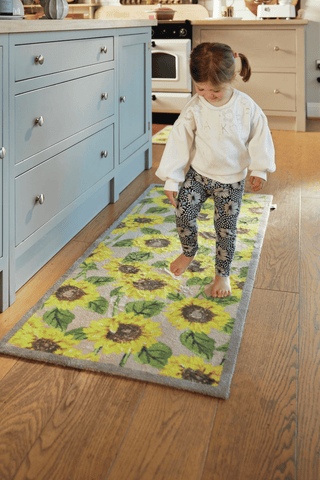 A young girl walking barefoot on a sunflower print kitchen runner