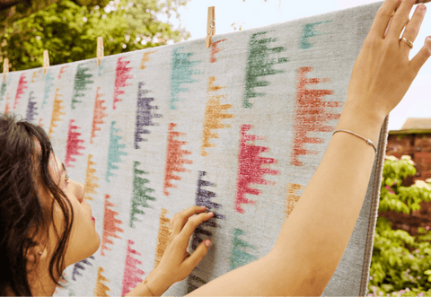 Girl hanging printed ikat eco-washable rug on washing line