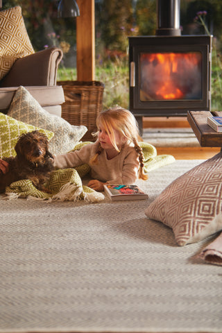 A young girl and a dog lying in front of the fire on a rug