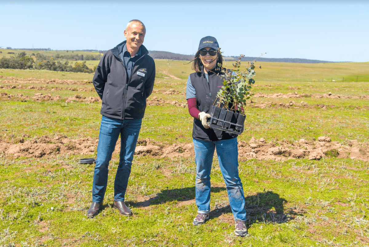 two people with seedlings at a reforestation site in Australia