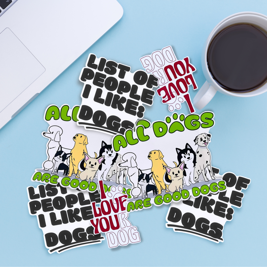 Stickers with dog illustrations and text about loving dogs, alongside a laptop and coffee on a blue surface.