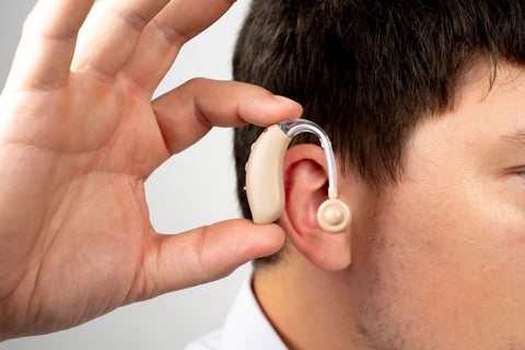 a asian man is holding beige hearing aid