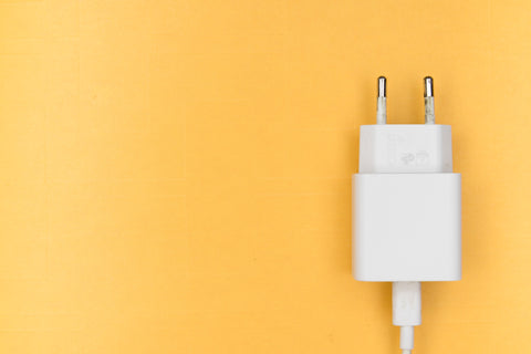 A white charging cable is placed on a yellow background