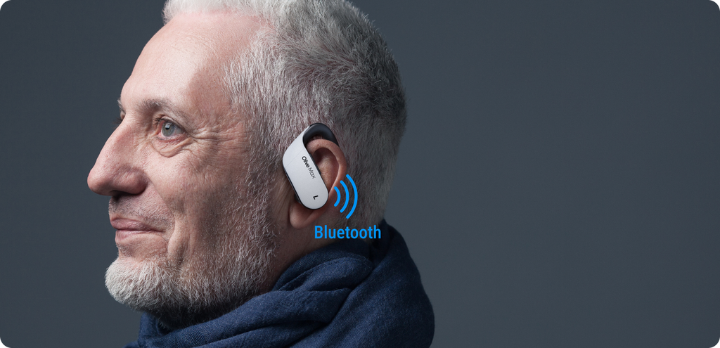 an old man is wearing bte hearing aids and besides him, there is bluetooth icon
