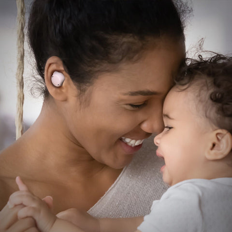 a woman with earbud hearing aids is holding baby boy