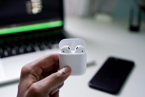 a hand is holding airpods in the case