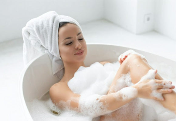 Woman in bath with towel around hair.