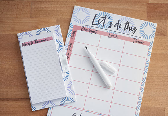 Meal planner notebook and pen on wooden table.