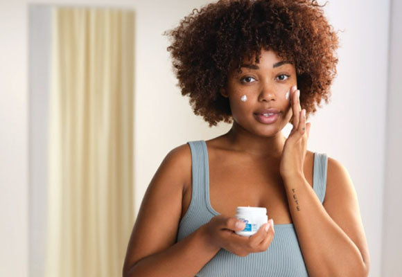 Woman applies moisturiser to cheeks.