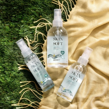 Three Skin So Soft dry oil bottles lie on the background of grass and a blanket.