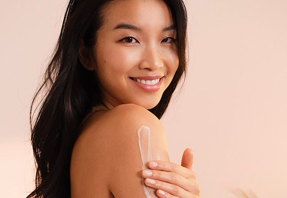 Summer skincare - model applying moisturiser to arm.