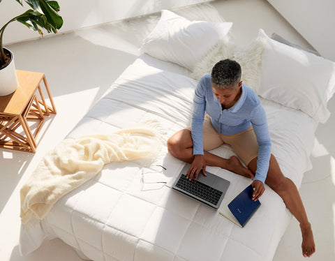 A woman from above on her laptop in bed