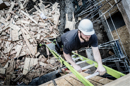 A man ascending an extension ladder at a construction site.