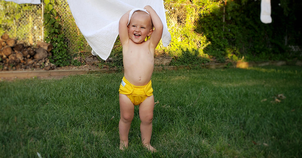 happy baby with yellow cloth diaper and cloth diaper laundry