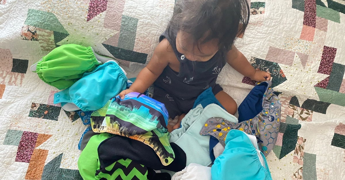 baby with a pile of cloth diapers