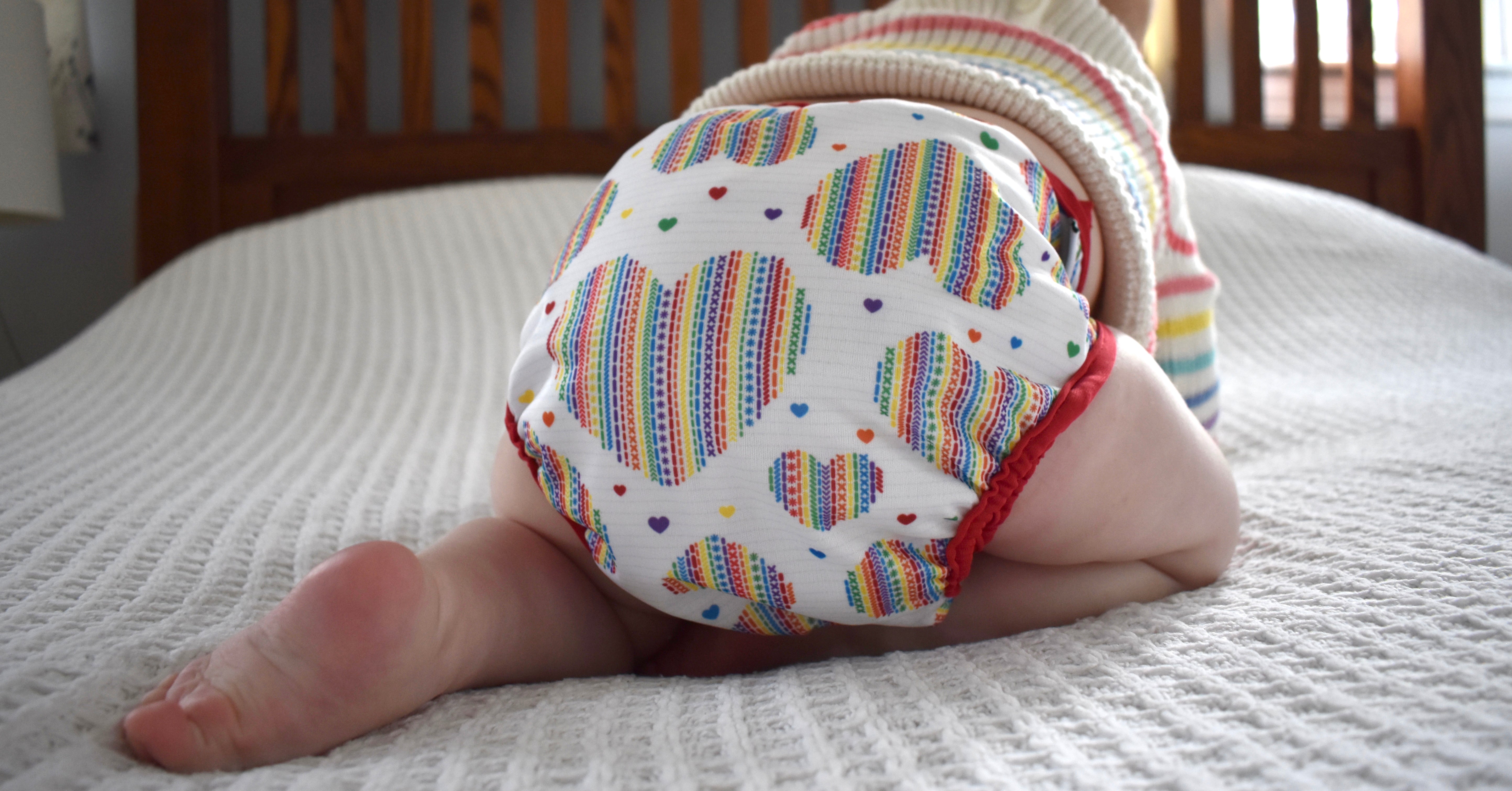 baby wearing a cloth diaper and crawling on a bed