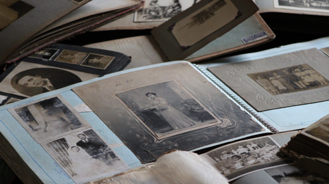 A photo of various old antique style portraits, being arranged into an album.