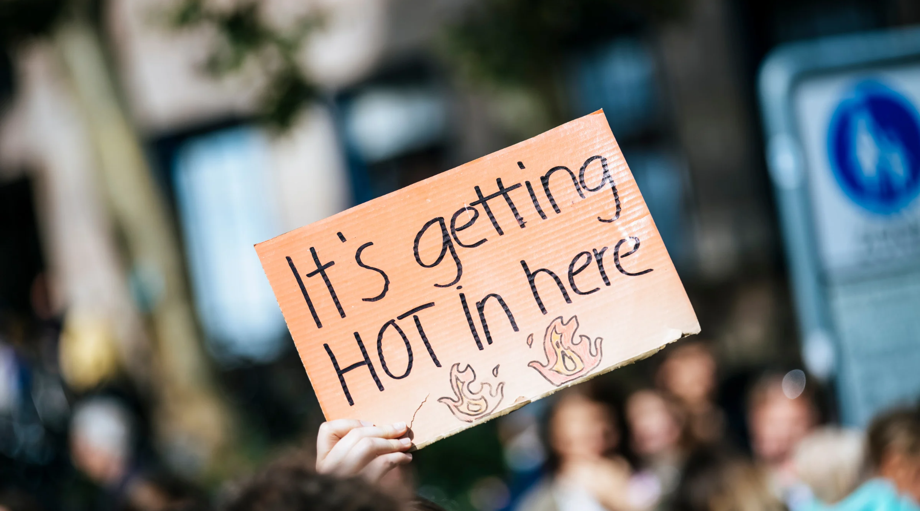 Close-up of a protest sign that says "it's getting hot in here"