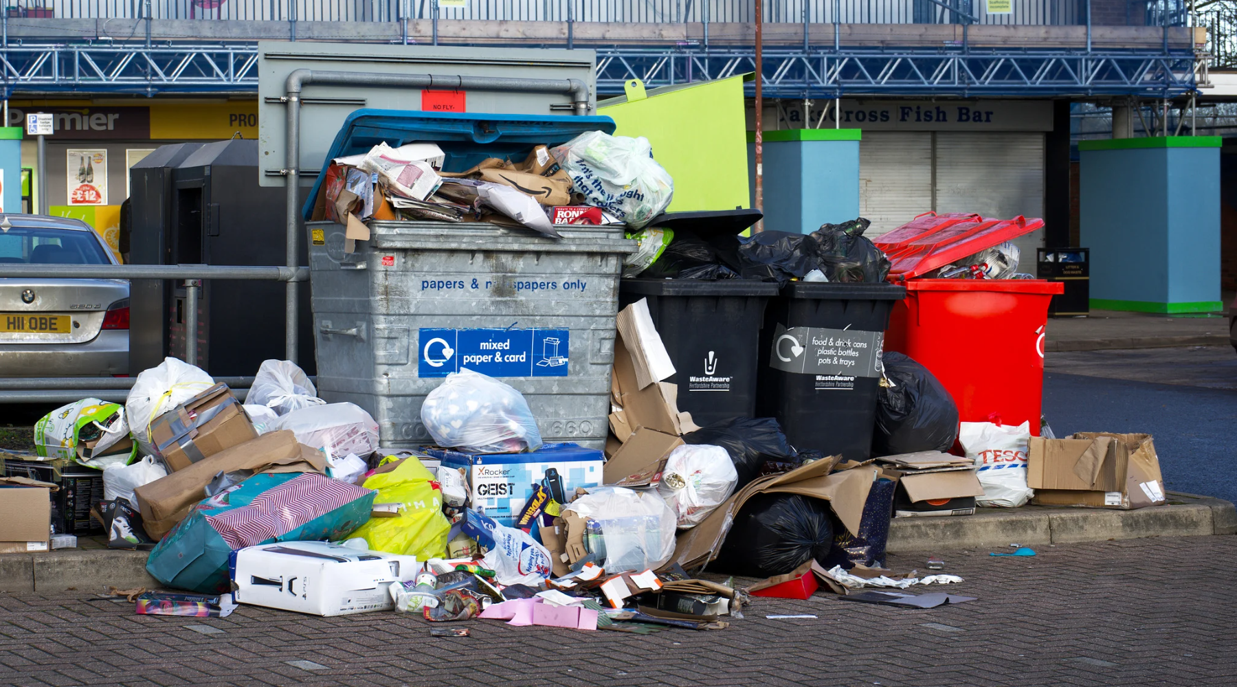 An overflowing dumpster in a parking lot.