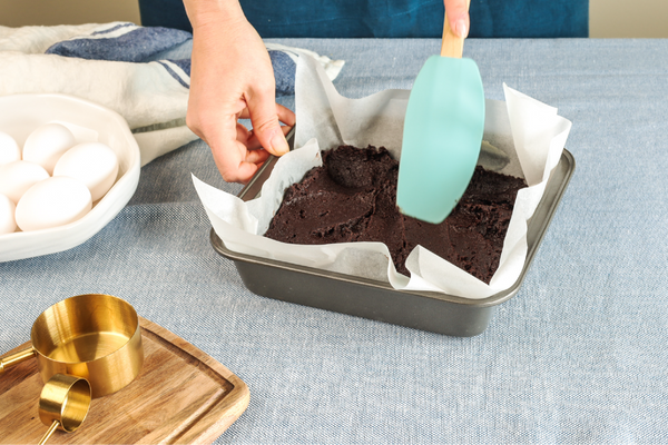 Spreading raw brownie batter into baking pan