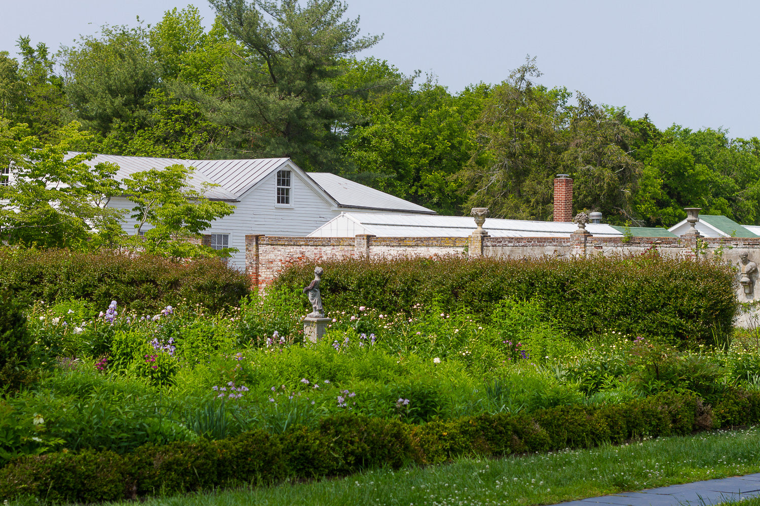 Large rose garden with statue and brick wall