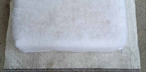 Cutting a seat cushion out of upholstery fabric.