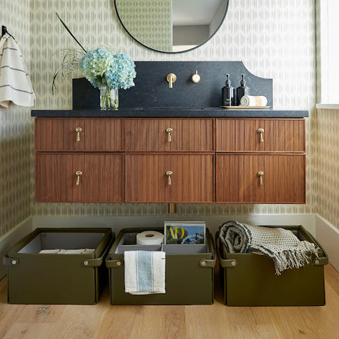 Green storage bins in bathroom under cabinets