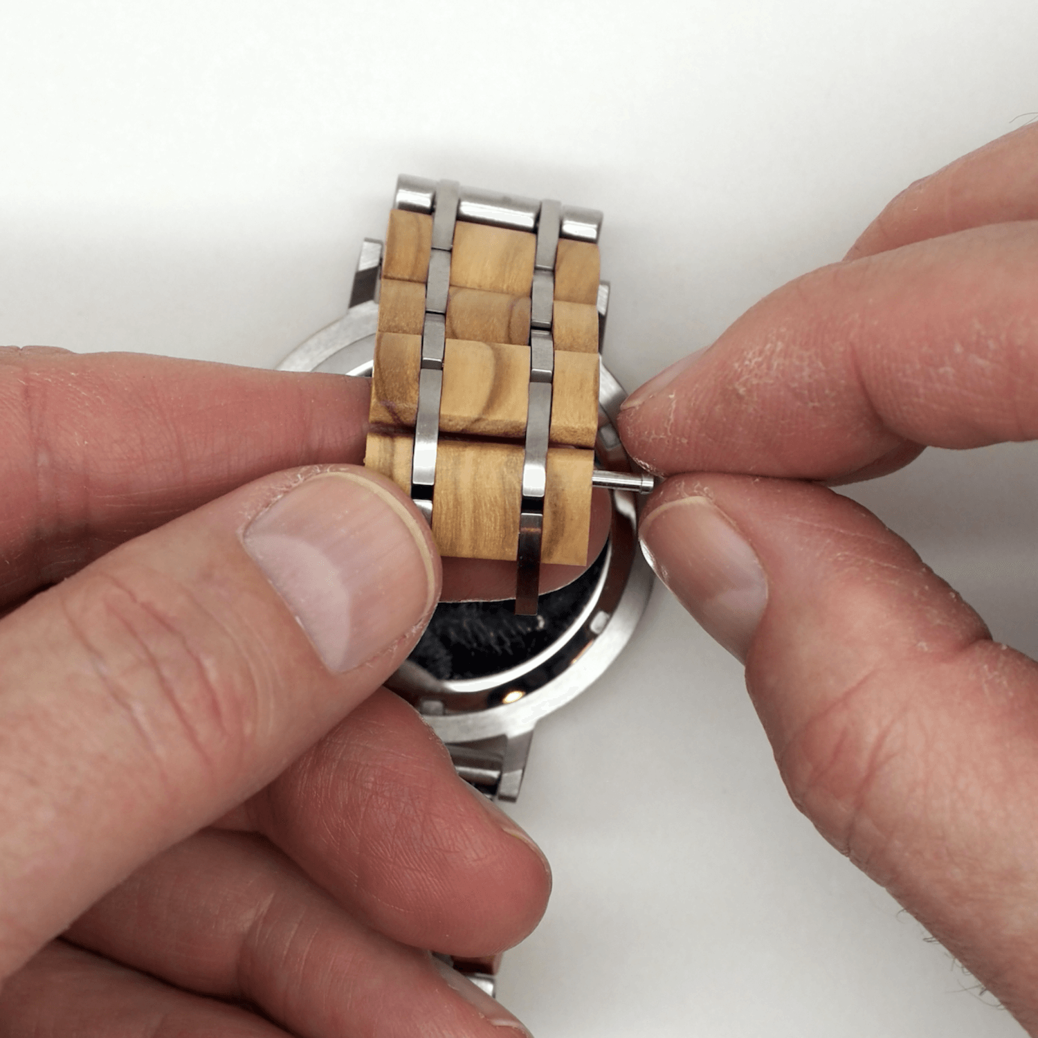 Person removing pin and wooden watch band link