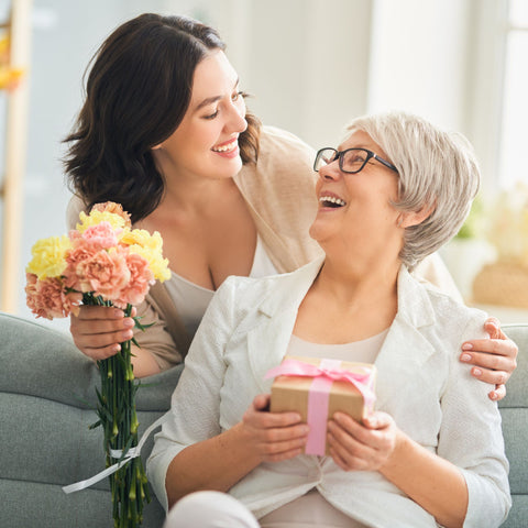 jeune femme offrant des fleur et un cadeau éco-responsable à sa maman pour la fête des mères