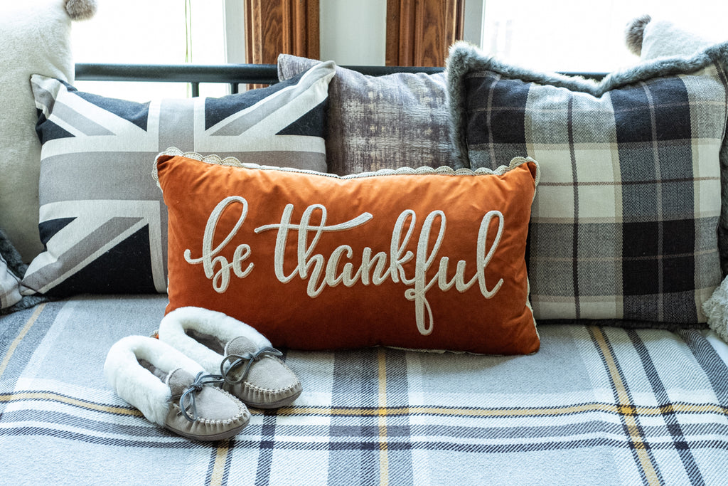 cozy sheepskin slippers next to a thankful autumn thanksgiving pillow cozy