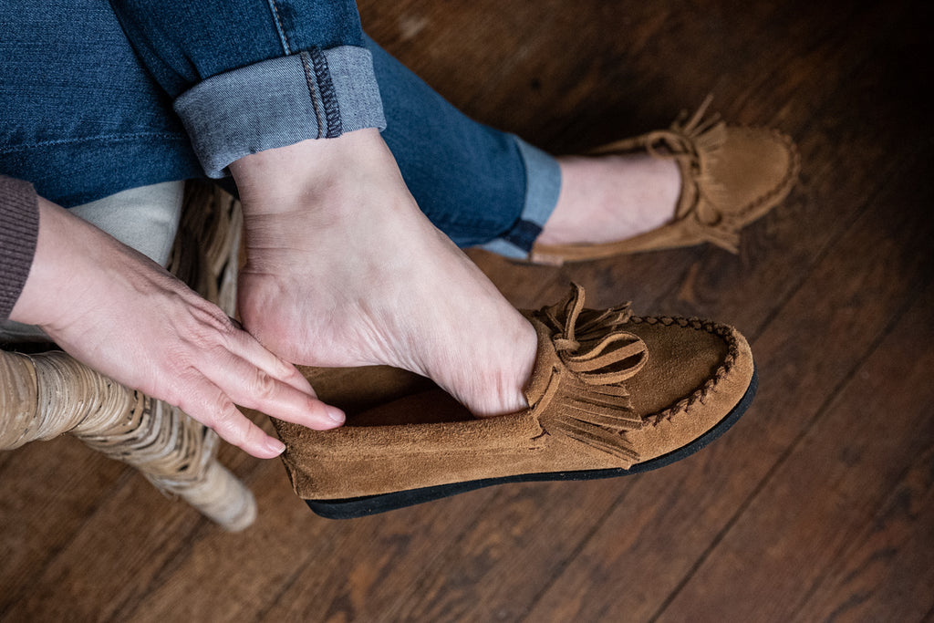slipping on a pair of Laurentian Chief moccasins for women