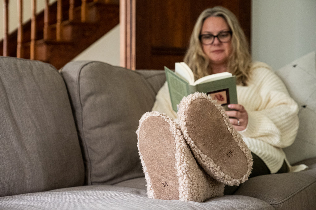 Cozy Winter slippers shearling reading on a couch with feet up