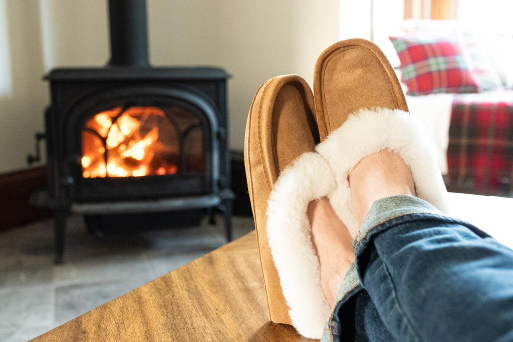 Cozy fireplace with man wearing warm sheepskin slippers