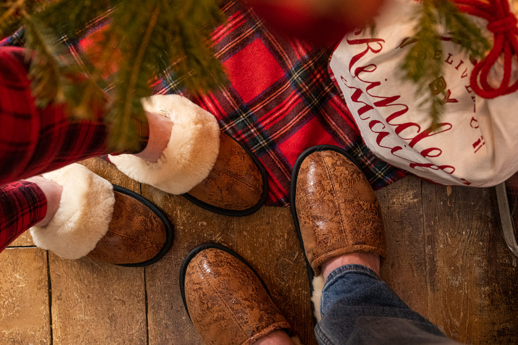 Men's and women's cozy sheepskin slip-on slippers under the tree