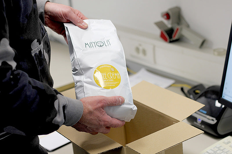 Versandmitarbeiter packt Kaffeetüte in Karton