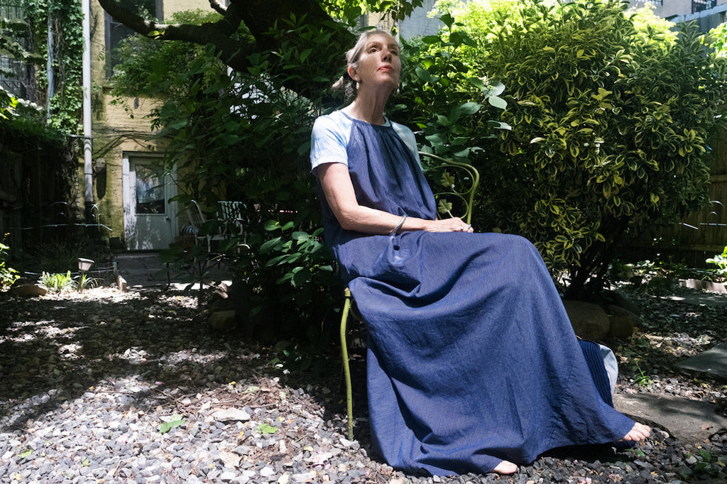 Susannah Thompson sitting in a garden wearing the M.PATMOS Laia Dress in Navy Stripe