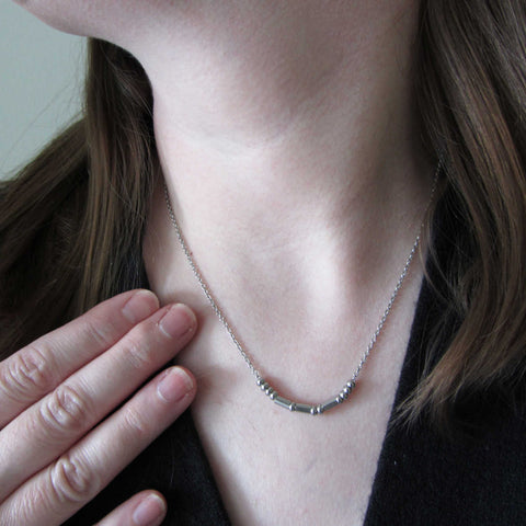 morse code necklace worn on person wearing black smart top