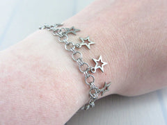 five small hollow star charms on a handmade chainmaille stainless steel chain bracelet on wrist