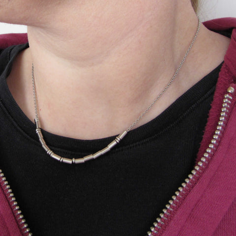 morse code necklace worn on person wearing black t-shirt and red zip top