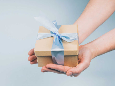 hands holding gift box tied with a blue ribbon