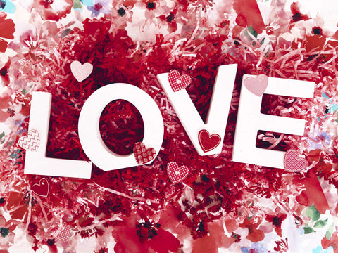 white letters spell love with red paper hearts