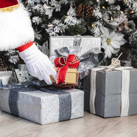 santa placing presents under a christmas tree