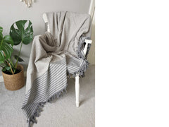 grey striped and diamond patterned throw blanket placed over wooden chair